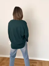 Remera verde con botones en el escote, de manga larga y corte recto.