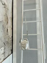 Bandolera plateada pequeña con diseño capitoneado, correa regulable con diseño combinado entre cintas de algodón, cuero y aritos metálicos.