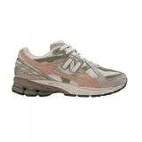 Championes New Balance modelo 1906R, con combinación de colores beige, verde oliva, rosado pálido y detalles en marrón oscuro. Presentan una construcción con malla transpirable, superposiciones de cuero sintético y gamuza, y tecnología de amortiguación N-ergy en la suela.