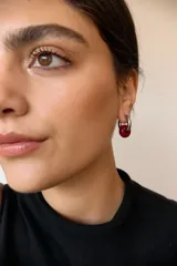 Aros de acero quirúrgico hipoalergénico con forma de argolla plateada y dije circular colgante de piedra natural color azul.