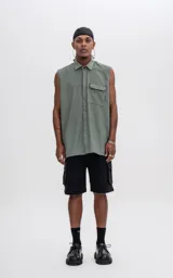 Camisa sin mangas color verde militar de calce oversize con doble bolsillo y detalle de remaches en el frente, confeccionada en tejido twill.