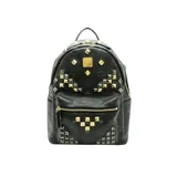 Mochila negra con estampado del logo de la marca y tachuelas metálicas doradas y plateadas. Tiene cierre bidireccional, asa superior, correas ajustables, dos compartimentos interiores (uno para tablet), bolsillos laterales y bolsillos con cierre interior y exterior.