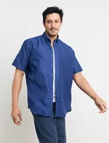 Camisa de manga corta azul con pequeños lunares blancos, cuello abotonado y bolsillo en el pecho.