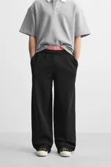 Pantalón jogger negro de corte ancho, confeccionado en tejido de algodón con interior de rizo. Cuenta con cintura elástica ajustable con cordón interior, bolsillos laterales y bolsillo trasero de parche.
