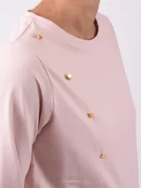Remera negra de manga larga con cuello redondo y detalle de botones dorados en el hombro.
