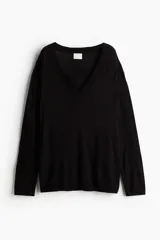 Sweater negro de punto fino, con escote en V pronunciado, corte holgado y hombros caídos.