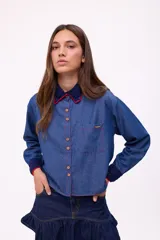 Camisa de denim azul con cuello y puños con detalles de crochet en azul marino y rojo.