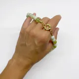 Collar de cuentas redondas de serpentina en tonos de verde claro y blanco, ensartadas con hilo verde y terminaciones y broche tipo anilla de acero con baño de oro.