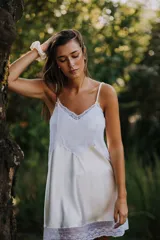 Camisón corto negro de satén con breteles finos y escote en V con puntilla blanca.