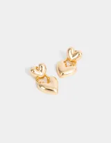 Aros colgantes cortos dorados con dos dijes en forma de corazón.