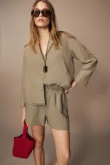 Shorts de tiro medio confeccionados en lino 100%. Cuentan con bolsillos laterales ocultos en la costura, bolsillos de parche en la parte trasera, cintura elástica, aberturas laterales en el bajo y cierre frontal con botones.