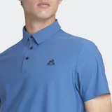 Remera polo de manga corta color azul, con cuello y tapeta de tres botones oscuros. Presenta un pequeño logo bordado en el pecho.