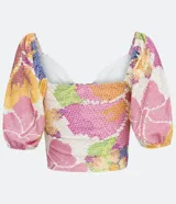 Top cropped de tejido tipo laise con estampado floral pixelado en tonos pastel (rosa, amarillo, azul, blanco). Presenta escote corazón con abertura central y lazo ajustable, y mangas cortas abullonadas.