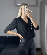 Blusa negra con estampado de lunares blancos, escote en V cruzado, mangas 3/4 abullonadas y hombreras. Talle único abarca hasta L.