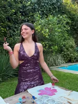 Vestido corto de lentejuelas color verde oliva, con escote en V, breteles finos cruzados en la espalda, cut-outs laterales y volado en el ruedo.