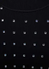 Minivestido negro de tejido de punto fino, corte ajustado, cuello redondo y manga larga. Decorado con strass plateados.