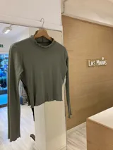 Remera gris de morley de algodón, de manga larga, con terminaciones fruncidas en cuello y mangas.