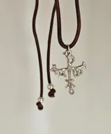 Collar con colgante de plata 950 con forma de crismón, que simboliza el nombre de Cristo en lengua griega. El colgante mide 2,7 cm x 1,1 cm y el largo del cuero es de 85 cm.