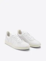 Zapatillas Veja V-10 de cuero blanco con logo lateral en forma de "V" y suela color crema.