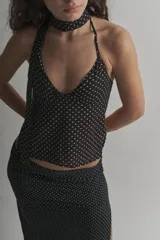 Top halter negro con lunares blancos, de tela tipo gasa, con espalda descubierta y lazos para atar al cuello y la espalda.