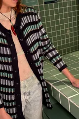 Cardigan vestido azul con rayas horizontales en tonos celeste, verde y beige. Tiene cuello redondo, mangas largas y cierre frontal con botones.