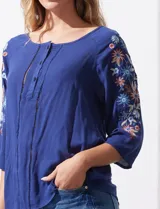 Blusa azul con escote redondo, mangas 3/4 con bordado floral y abertura central con botones. Marca Forgotten Grace.