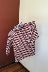 Camisa estampada con rayas diagonales y flores rojas, con botones en la parte delantera y en los puños.