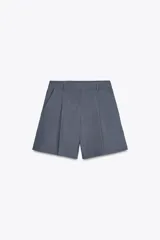 Bermudas de tiro alto color gris, con bolsillos delanteros y falso bolsillo con solapa en la espalda. Detalle de pinzas en el delantero y cierre frontal con cremallera y gancho metálico.