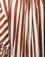 Falda midi de tul con estampado a rayas verticales en tonos marrón y blanco. Tiene volados verticales y cintura elastizada.