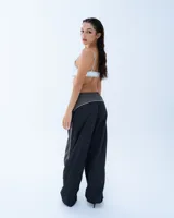Pantalón deportivo negro con recortes en gris y vivos blancos. Tiro medio, corte holgado, cintura elastizada y cierre en los tobillos.