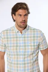 Camisa de manga corta con estampado a cuadros en tonos verde, beige y celeste. Modelo slim fit con bolsillo en el pecho.