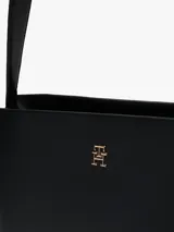 Cartera satchel negra de Tommy Hilfiger con acabado granulado, cierre de cremallera, asa superior, correa extraíble ajustable, bolsillo interior con cremallera e insignia del monograma TH en la parte delantera.