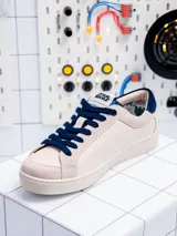 Zapatillas bajas de cuero color crema con detalles en azul marino y suela blanca. Presentan el logo de Star Wars en la lengüeta y el dibujo de R2-D2 en el lateral.