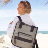Mochila cartera color verde militar con detalles en negro. Tiene dos bolsillos frontales con cierre y correas ajustables para usar como mochila o al hombro.