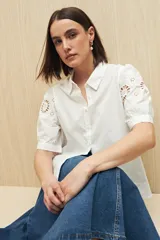 Camisa blanca de mangas cortas abullonadas con calados florales.