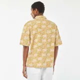 Camisa de manga corta color mostaza con estampado de palmeras en blanco.