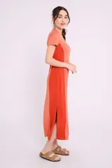 Vestido largo de tejido de punto acanalado color beige claro, con paneles laterales lisos en color marrón. Tiene mangas cortas y cuello redondo.