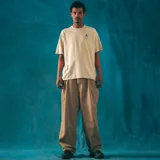 Remera manga corta color crudo, corte oversize, con estampa en la espalda que incluye el logo de la marca Kaboa Industries y la frase "Más barrio que moda".