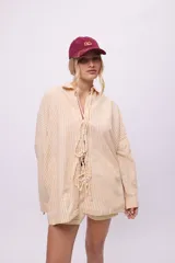 Camisa blanca de lino y algodón, con cuello clásico, cierre frontal con lazos y mangas largas abullonadas con puños ajustables con lazos.