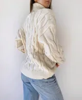 Polerón de punto en color crema, con diseño de trenzado y cuello alto.