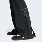 Pantalón deportivo Adidas Adibreak negro con logo de Adidas en la pierna. Tiene cintura elástica con cordón ajustable, bolsillos laterales y botones a presión a los lados.