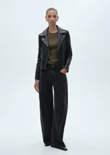 Chaqueta de cuero ovino negra, corte slim, con cuello con solapa, cierre frontal asimétrico con cremallera, mangas largas con cremallera en los puños y dos bolsillos laterales con cremallera.