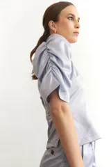 Blusa de seda color negro con escote en V y cierre lateral, con mangas abullonadas.