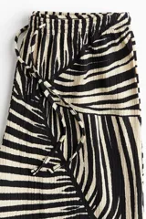 Pantalón de punto de corte holgado con piernas amplias, tiro alto, cintura elástica y cordón para ajustar. Estampado de hojas de palmera en blanco y negro.