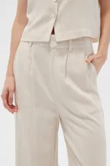 Pantalón de viscosa color beige, de corte ancho y tiro alto, con bolsillos laterales.