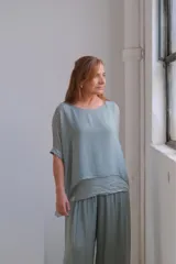 Blusa color verde agua, de corte holgado, con mangas cortas y detalle de lentejuelas en los puños y en el ruedo.