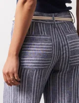 Pantalón de lino a rayas verticales azules y blancas, con corte ancho, pretina con pasadores, cierre y botones. Incluye cinto de soga con nudo.