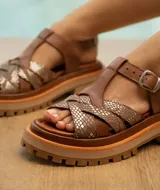 Sandalias de cuero vacuno color marrón con tiras cruzadas con estampado animal print dorado, hebilla lateral y doble suela de goma deportiva.