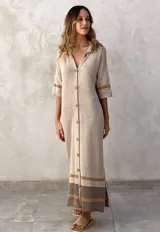 Vestido largo de tejido de punto color marrón topo, con cuello polo y cierre frontal de botones. Presenta detalles de rayas grises en las mangas y un bloque de color beige y gris en el ruedo. Tiene aberturas laterales.