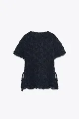 Top negro de punto con textura arrugada, cuello redondo, mangas cortas y lazos laterales.